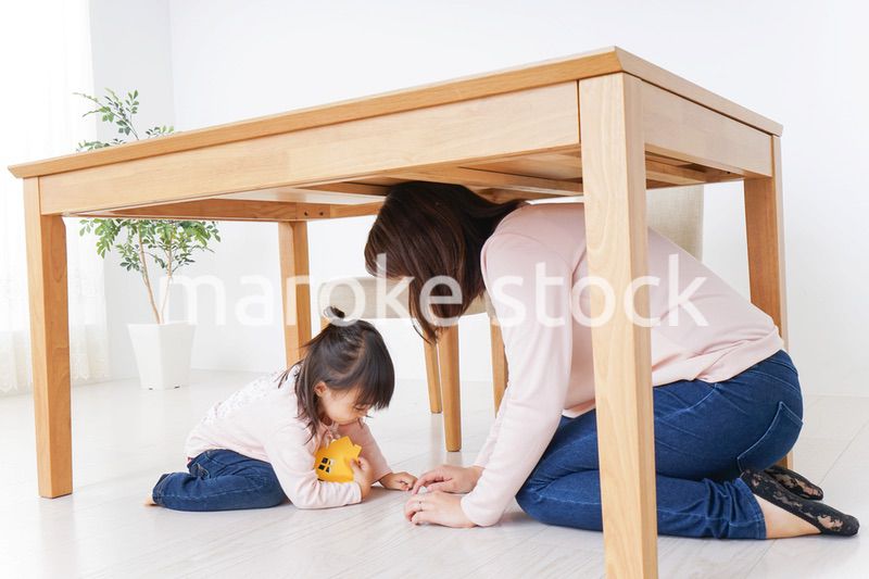 机の下に避難する親子