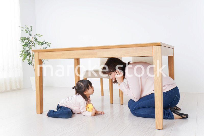 机の下に避難する親子