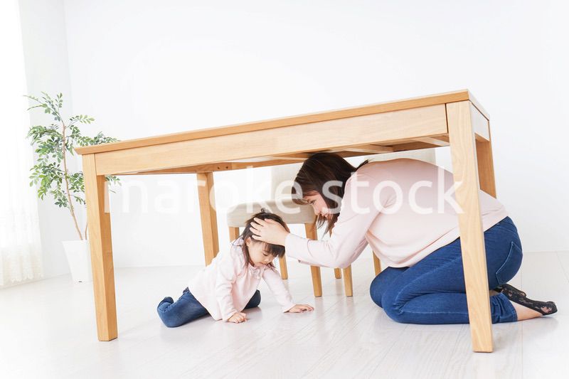 机の下に避難する親子