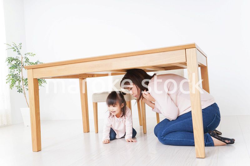 机の下に避難する親子