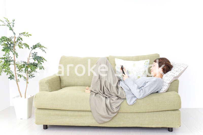 寝転んでスマホを使う女性