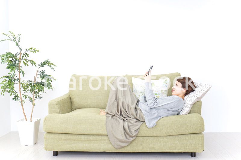寝転んでスマホを使う女性