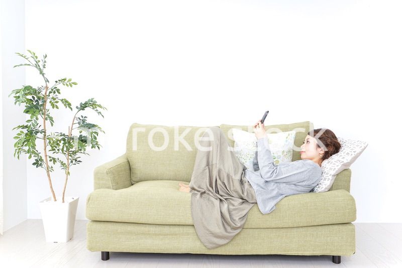 寝転んでスマホを使う女性