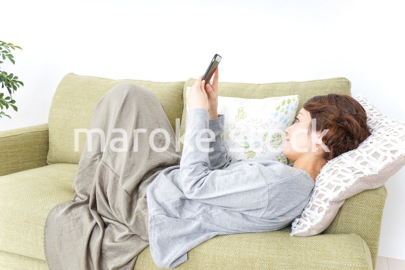 寝転んでスマホを使う女性