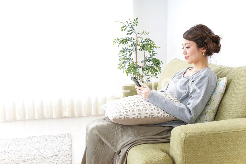 寝転んでスマホを使う女性