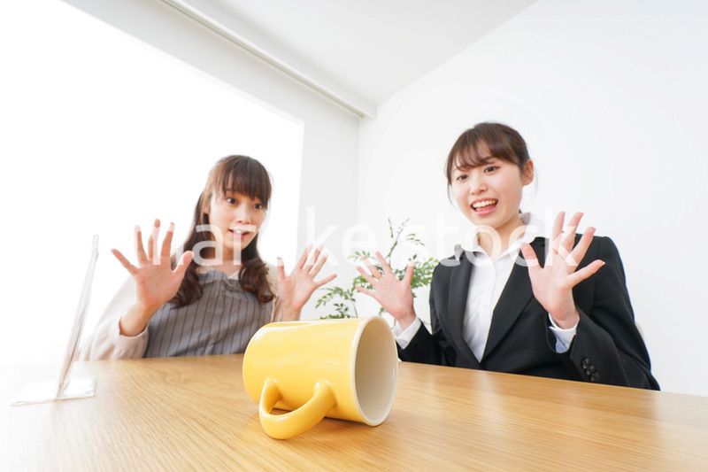 コーヒーカップが倒れ、驚く女性