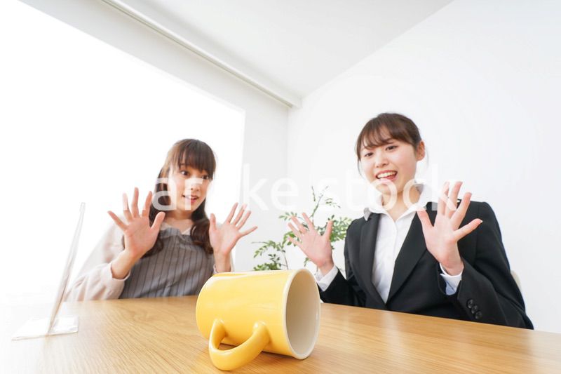 コーヒーカップが倒れ、驚く女性