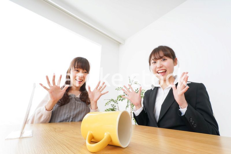 コーヒーカップが倒れ、驚く女性
