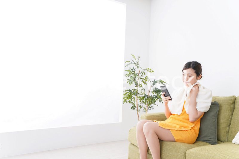 お風呂上がりにスマホをいじる女性