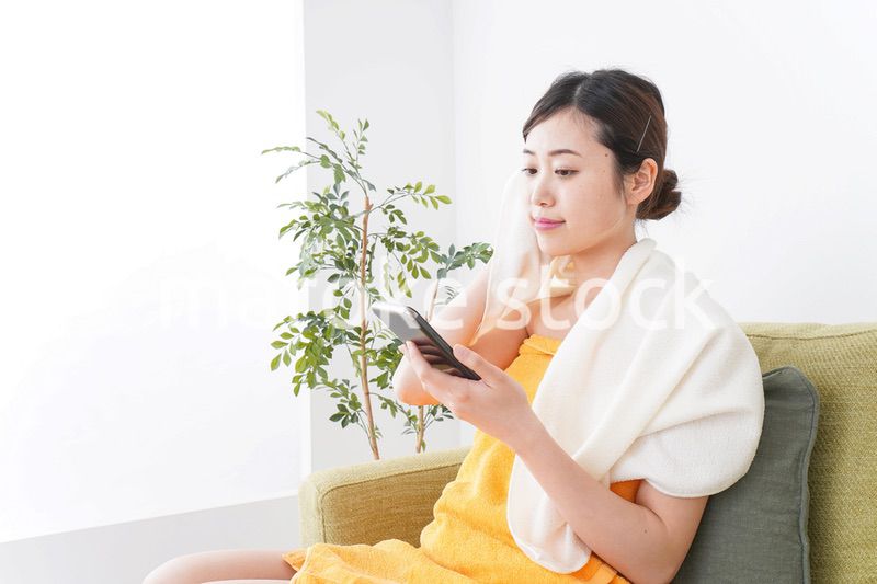 お風呂上がりにスマホをいじる女性