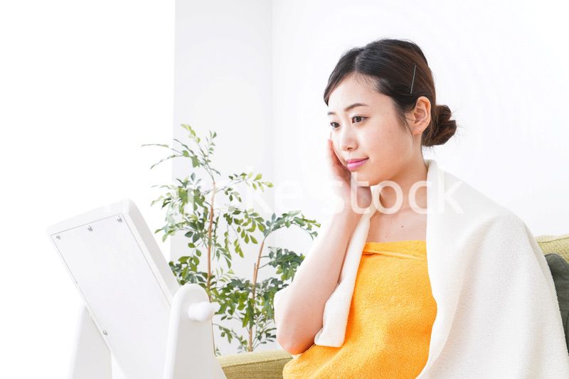 部屋でスキンケアをする若い女性