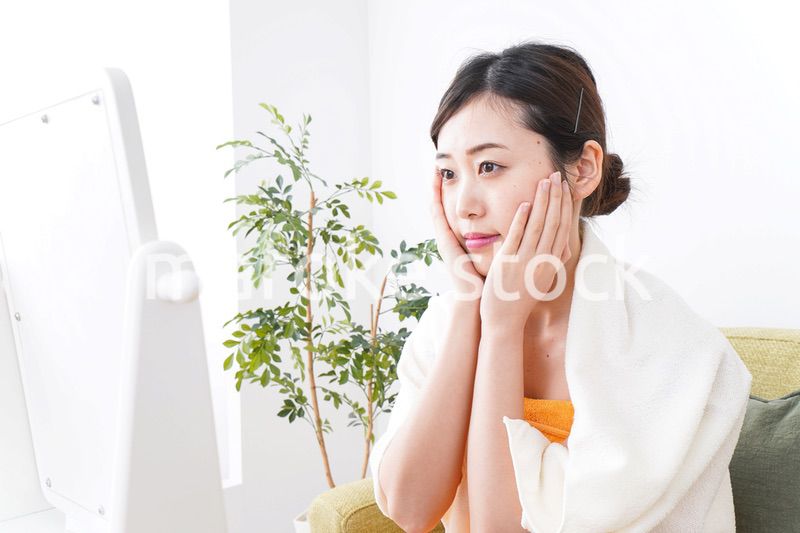 部屋でスキンケアをする若い女性