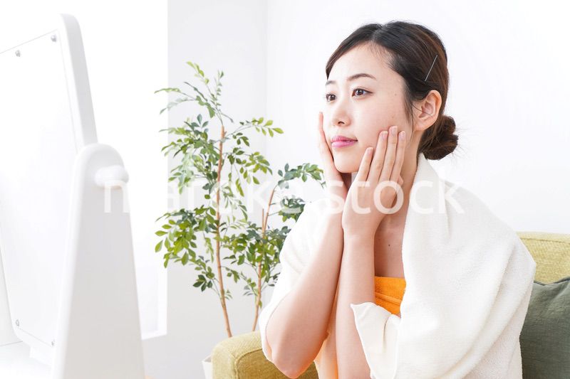 部屋でスキンケアをする若い女性
