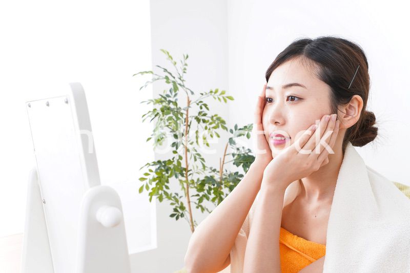 部屋でスキンケアをする若い女性