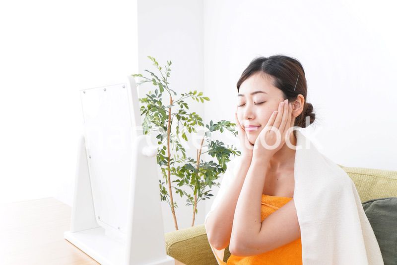 部屋でスキンケアをする若い女性