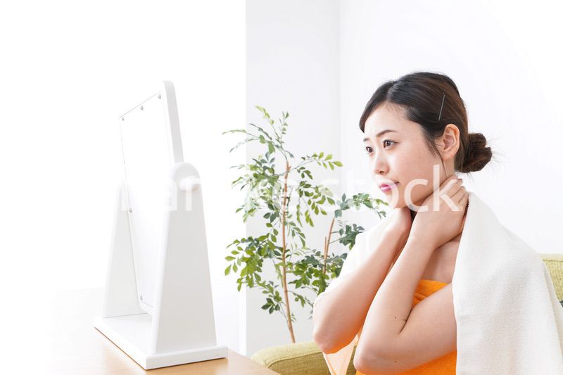 部屋でスキンケアをする若い女性