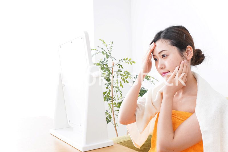 部屋でスキンケアをする若い女性