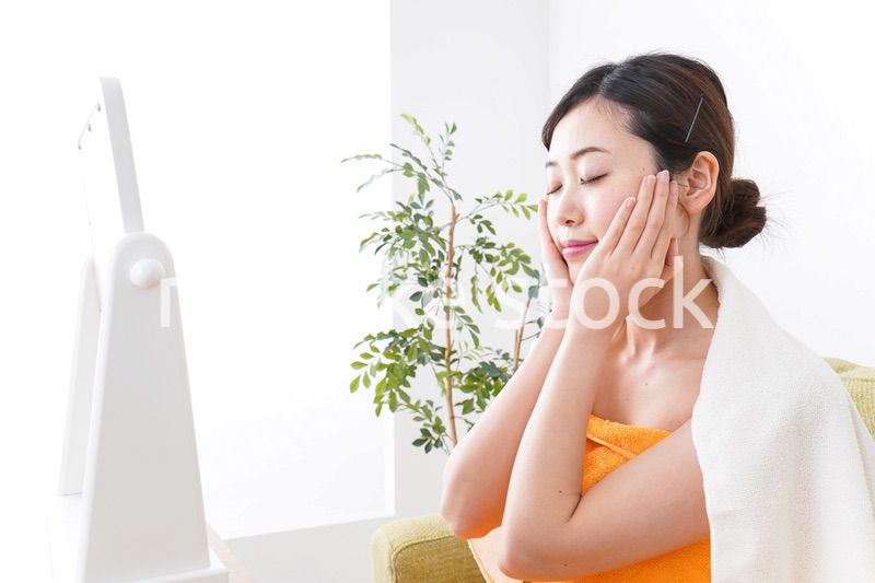 部屋でスキンケアをする若い女性
