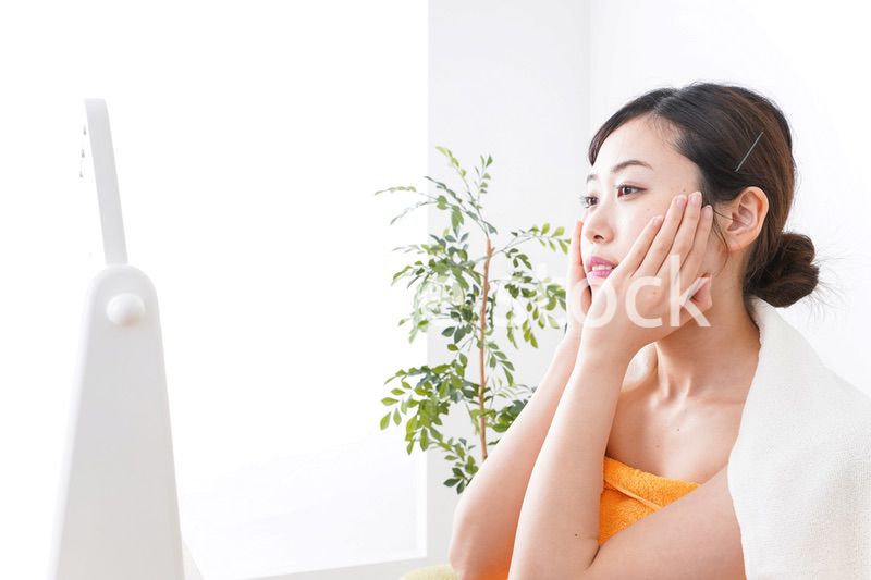 部屋でスキンケアをする若い女性