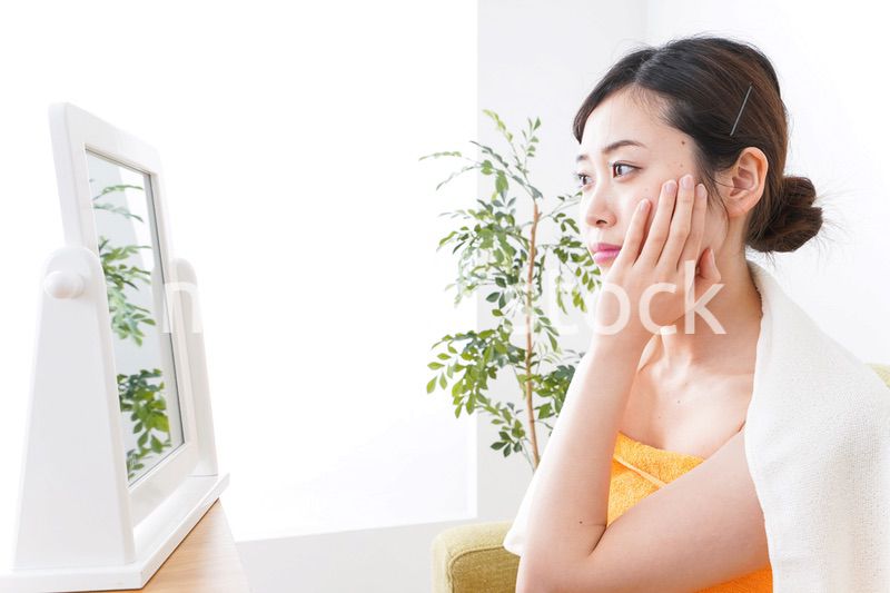 部屋でスキンケアをする若い女性