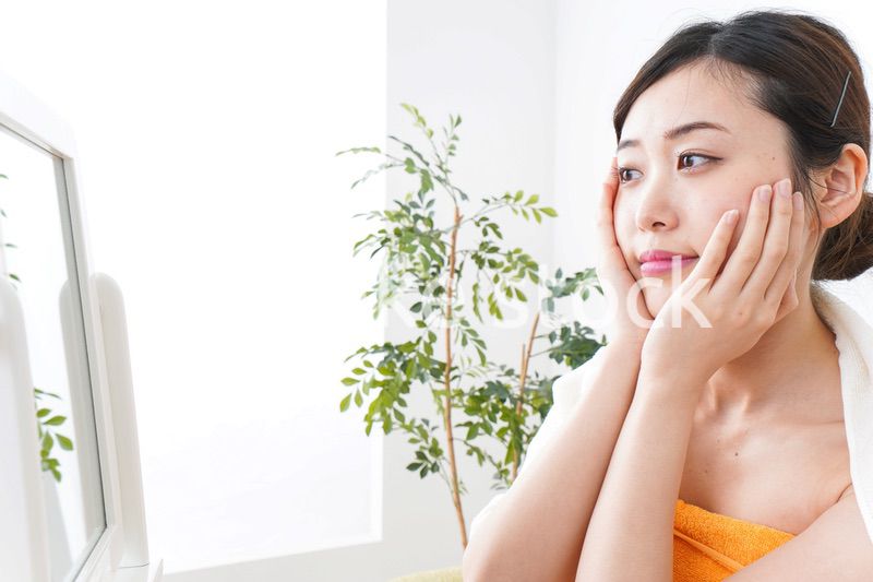 部屋でスキンケアをする若い女性