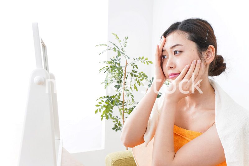 部屋でスキンケアをする若い女性