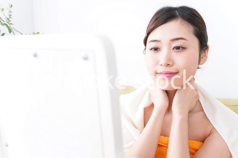 部屋でスキンケアをする若い女性