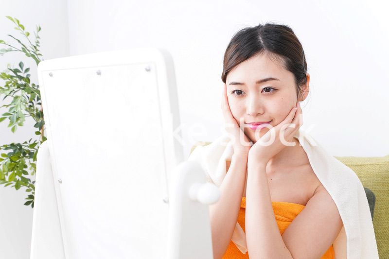 部屋でスキンケアをする若い女性