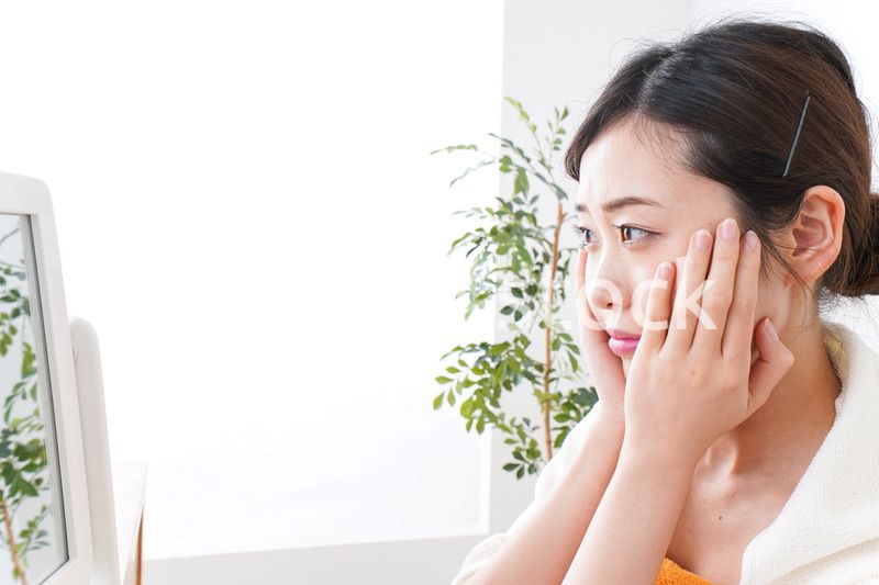 部屋でスキンケアをする若い女性