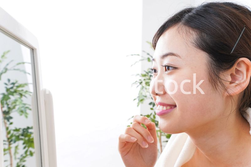 部屋でスキンケアをする若い女性