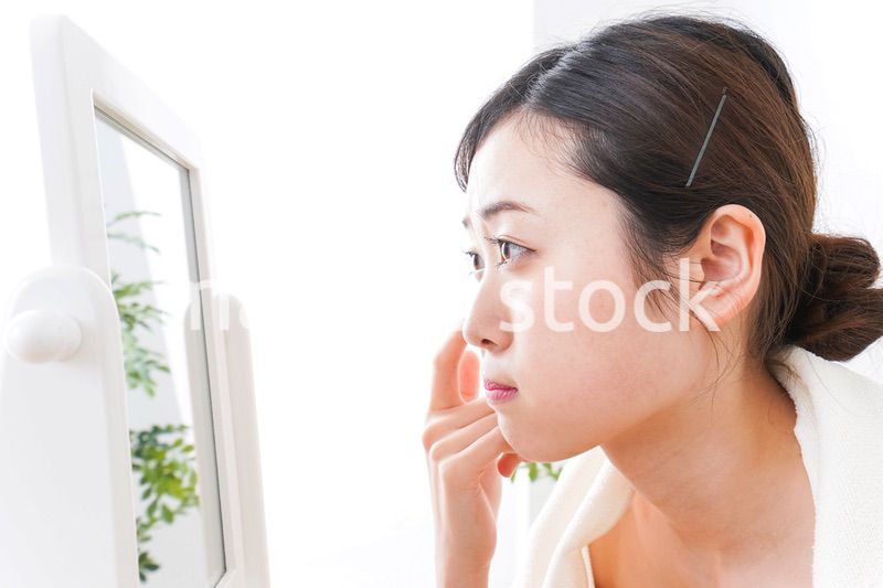 部屋でスキンケアをする若い女性