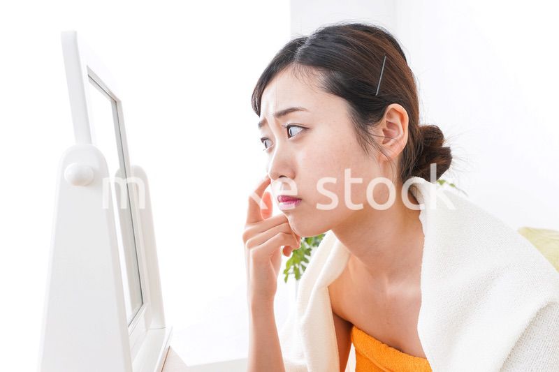 部屋でスキンケアをする若い女性