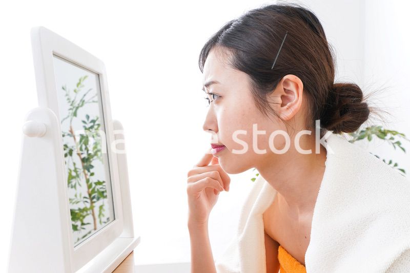 部屋でスキンケアをする若い女性