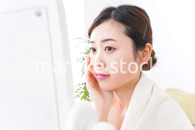 部屋でスキンケアをする若い女性