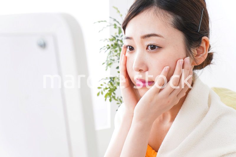 部屋でスキンケアをする若い女性