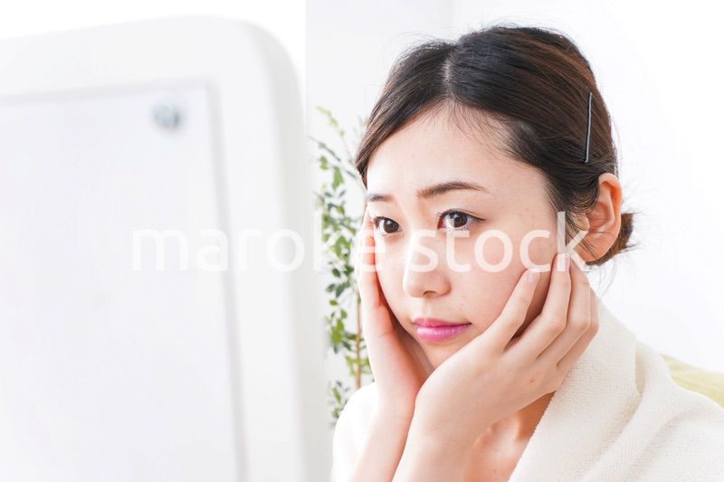 部屋でスキンケアをする若い女性