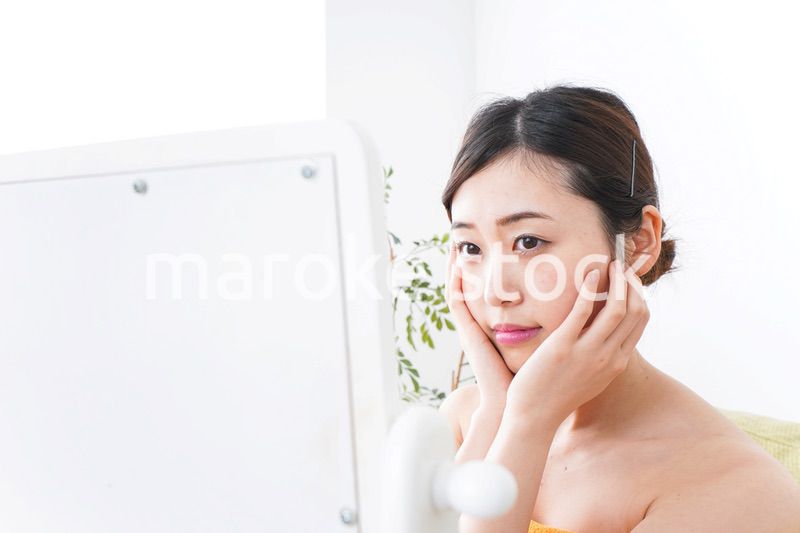 部屋でスキンケアをする若い女性