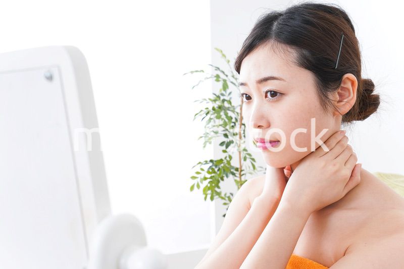 部屋でスキンケアをする若い女性