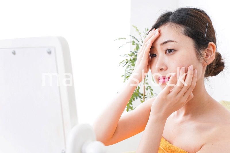 部屋でスキンケアをする若い女性