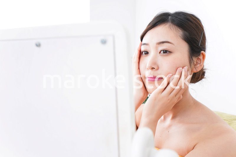 部屋でスキンケアをする若い女性