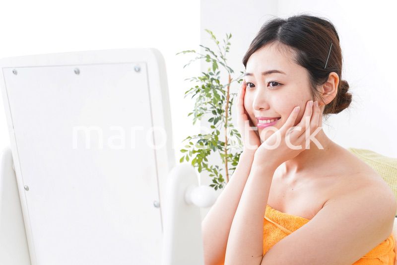 部屋でスキンケアをする若い女性