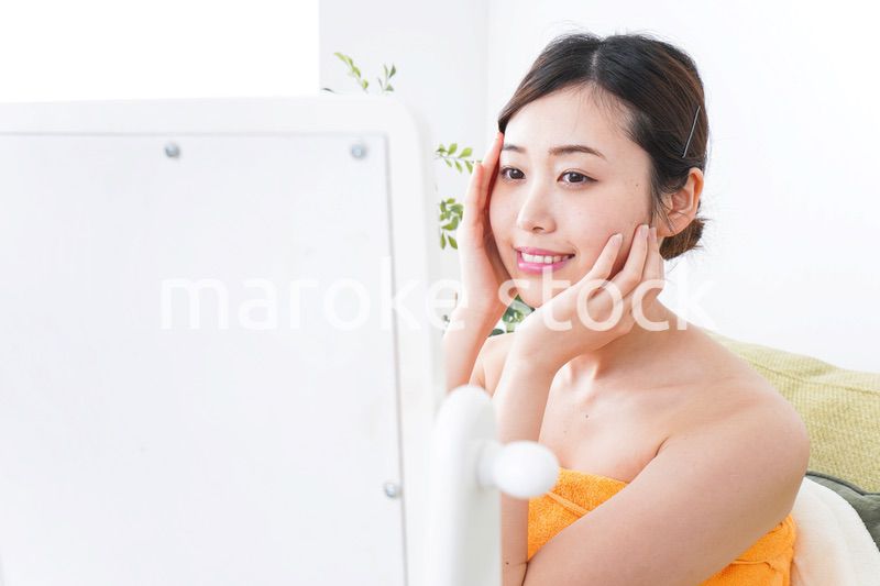 部屋でスキンケアをする若い女性