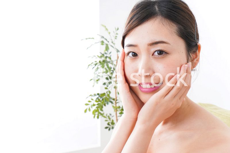 部屋でスキンケアをする若い女性