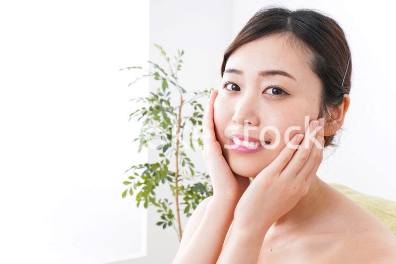 部屋でスキンケアをする若い女性