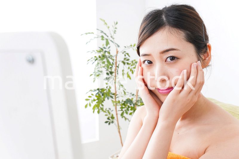 部屋でスキンケアをする若い女性