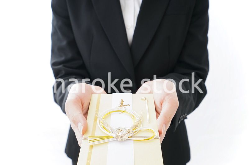 祝儀袋を渡すスーツ姿の女性