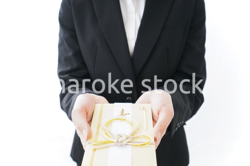 祝儀袋を渡すスーツ姿の女性