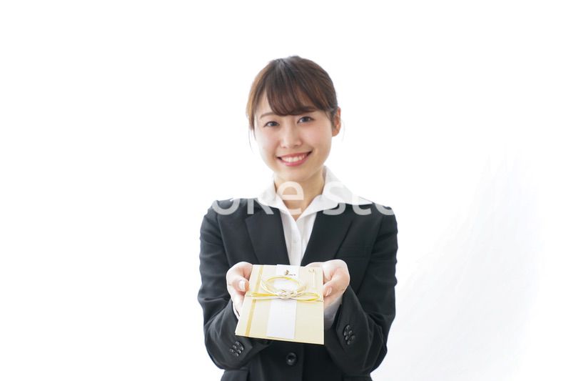祝儀袋を渡すスーツ姿の女性
