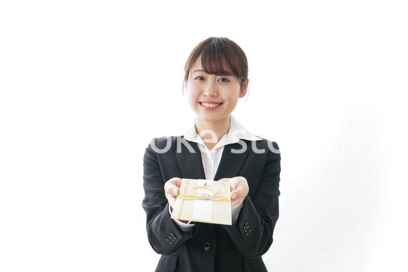 祝儀袋を渡すスーツ姿の女性