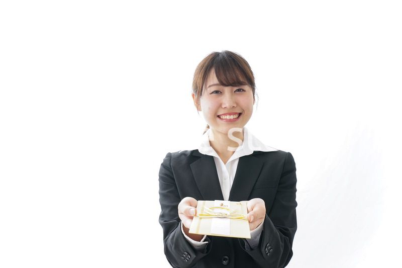 祝儀袋を渡すスーツ姿の女性